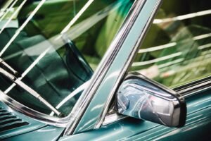 Detailed image of a luxury car's side mirror, window, and chrome trim.