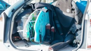 Car trunk loaded with surfboards and wetsuits, ready for beach adventure.