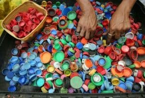 A vibrant assortment of plastic bottle caps being sorted by hand for recycling in Manila.