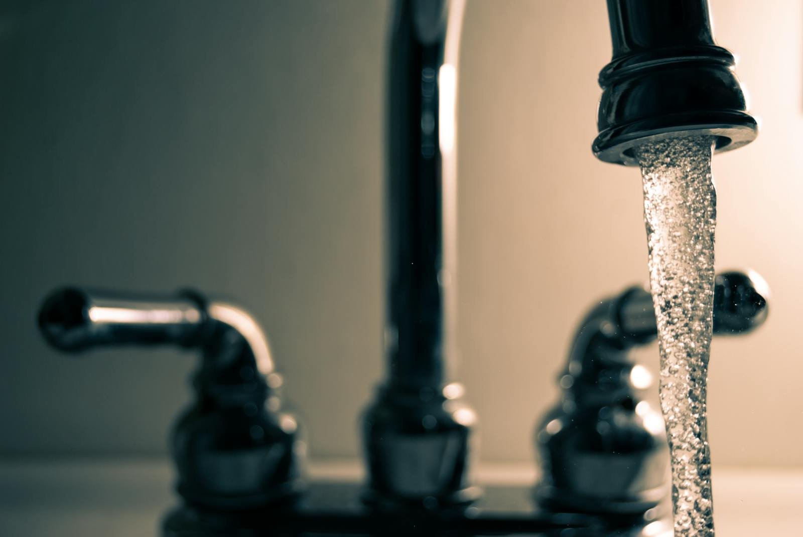 A detailed shot of water flowing from a steel faucet, ideal for themes on cleanliness or plumbing.