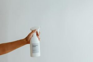 Close-up of a hand holding a multi-purpose cleaner spray bottle against a white background.