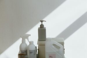 A collection of cleaning products on a minimalist background with dramatic shadows.