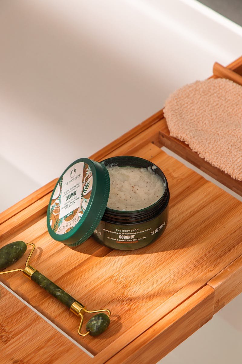 Elegant bath arrangement featuring exfoliating cream and jade roller on a bamboo tray.