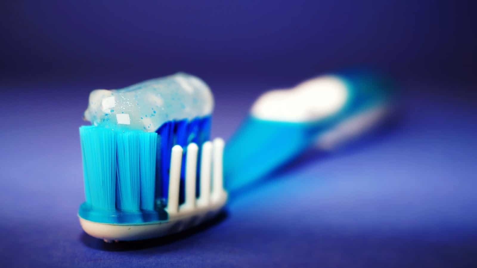 Macro shot of a toothbrush with blue toothpaste and blurred background.