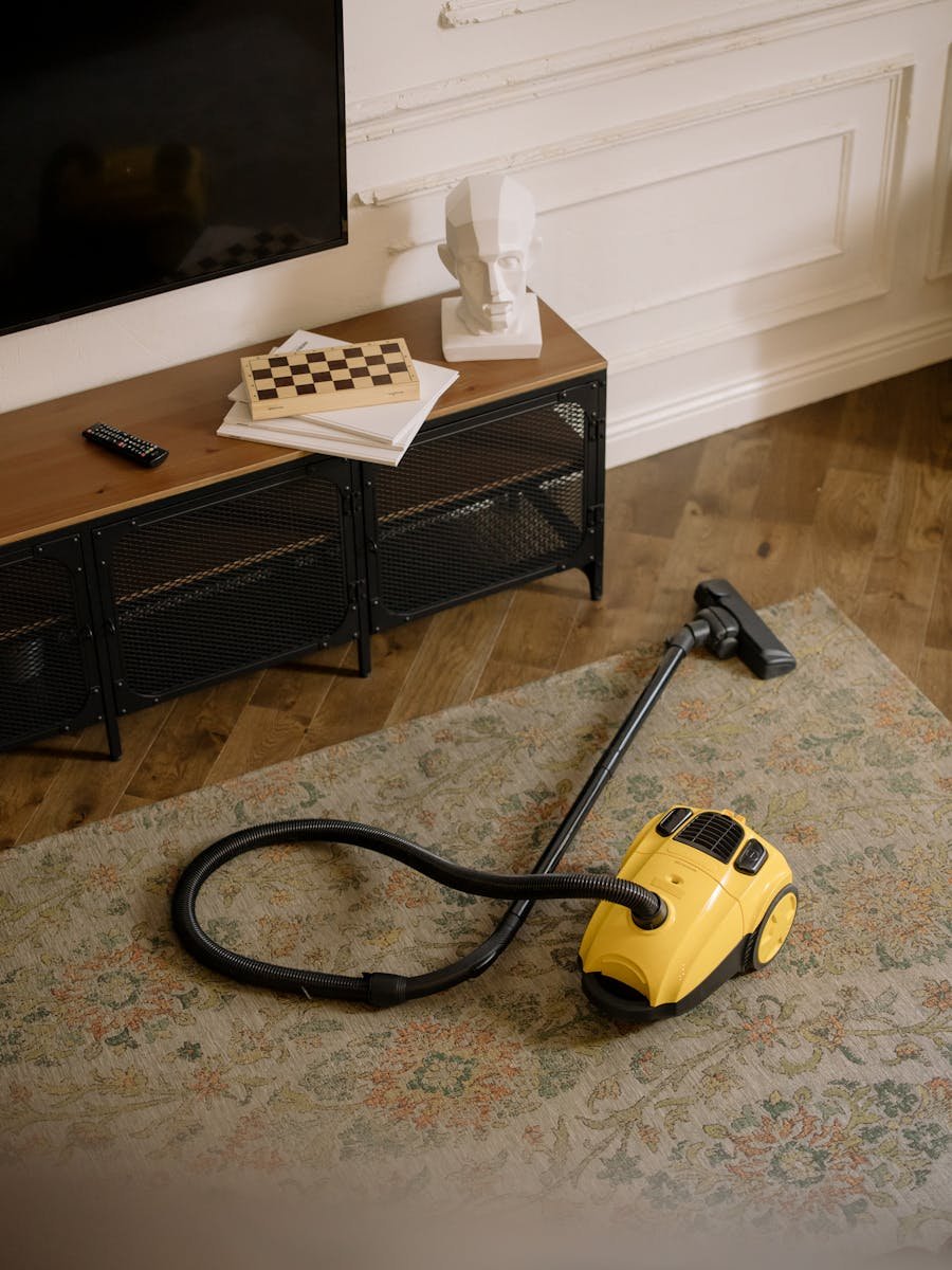 A stylish living room with a yellow vacuum cleaner on the rug, showcasing home cleanliness.