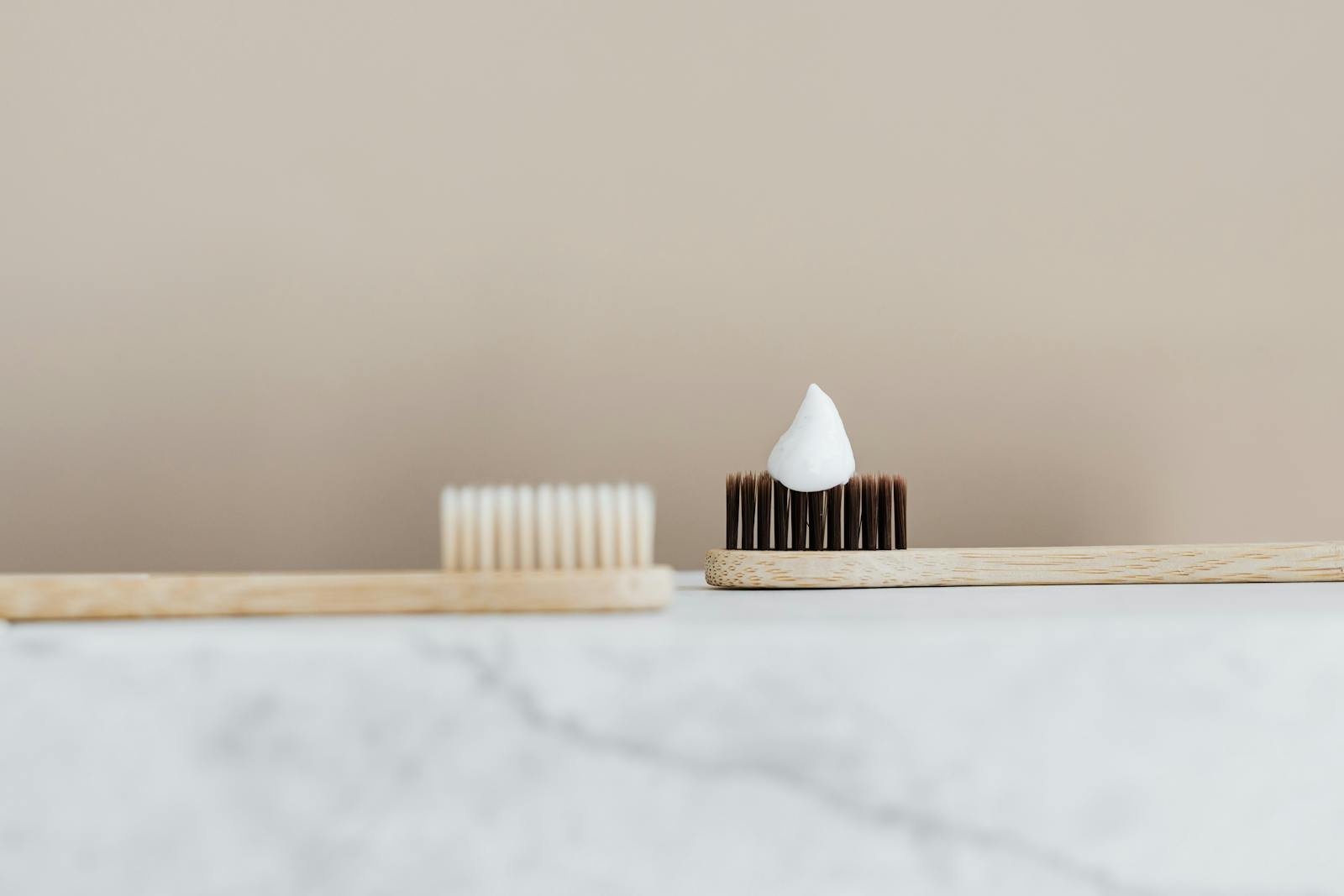 Close-up of a bamboo toothbrush with toothpaste in a minimalist setting.