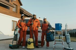 Group of workers in protective gear standing beside equipment outdoors.