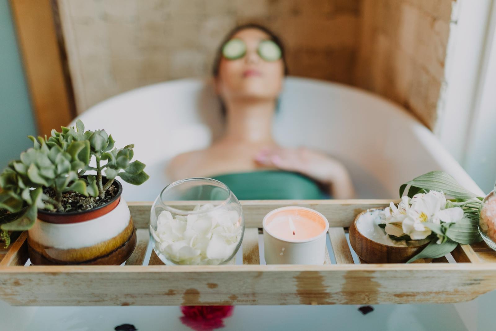 Woman relaxing in a bathtub with a candle and plants, enjoying a serene spa experience.