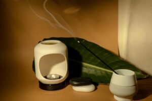 Serene aroma therapy setup featuring an incense stick and candle against a natural backdrop.