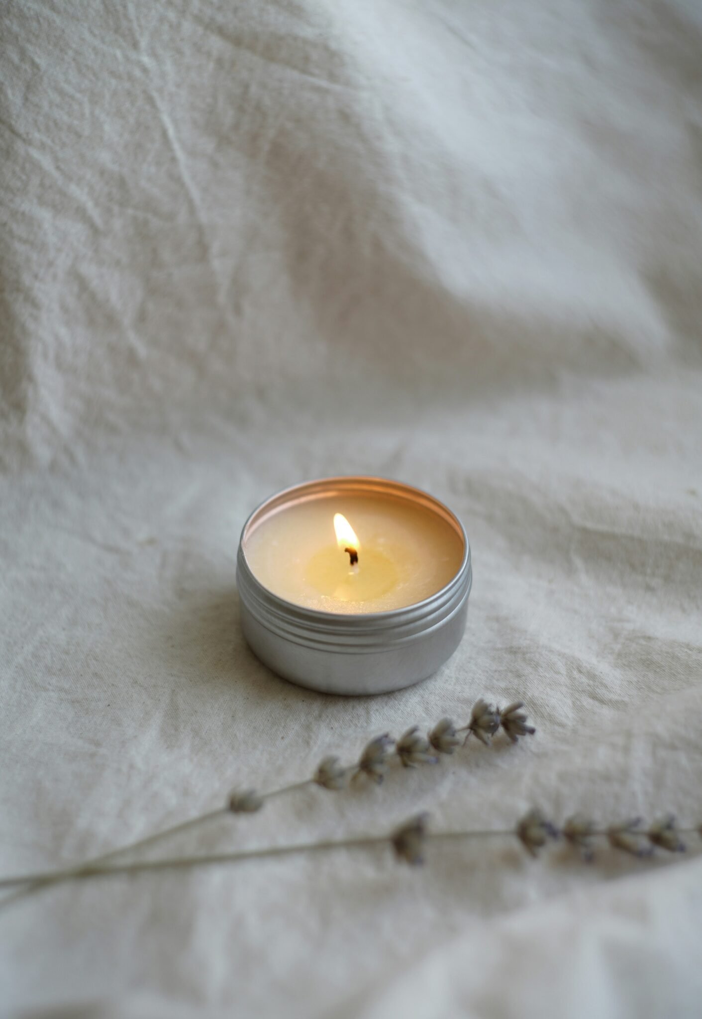 a white candle sitting on top of a white sheet